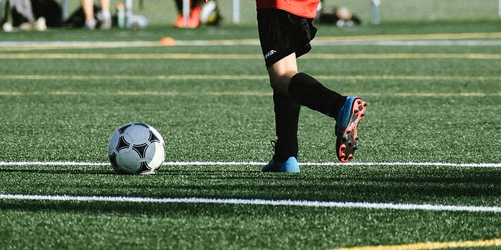 Cropped-legs-kicking-soccer-ball-field