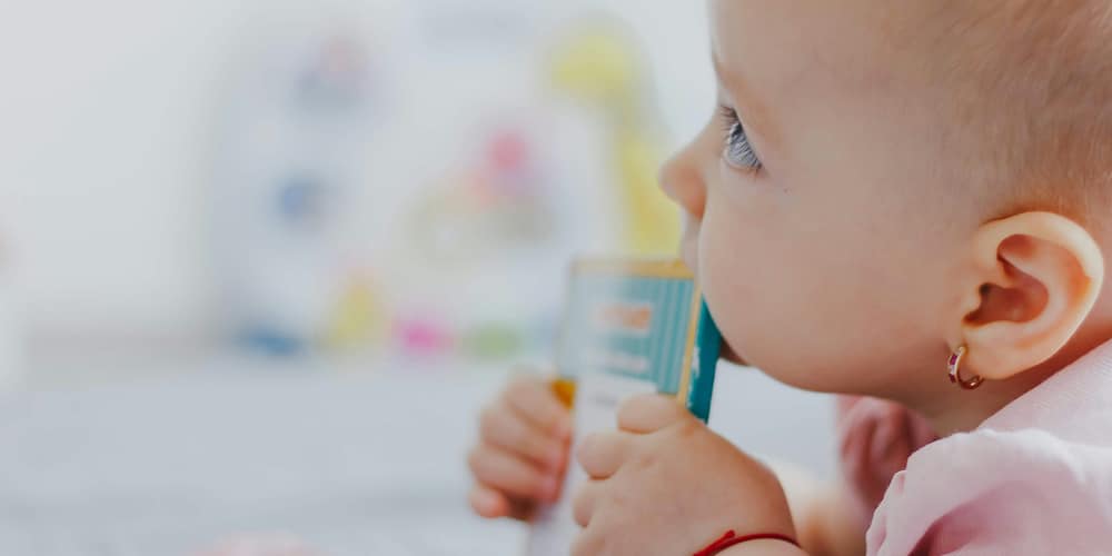 A baby girl chewing on a book