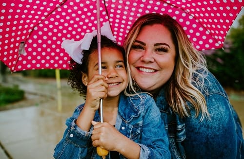 Woman-daughter-hugging-under-umbrella